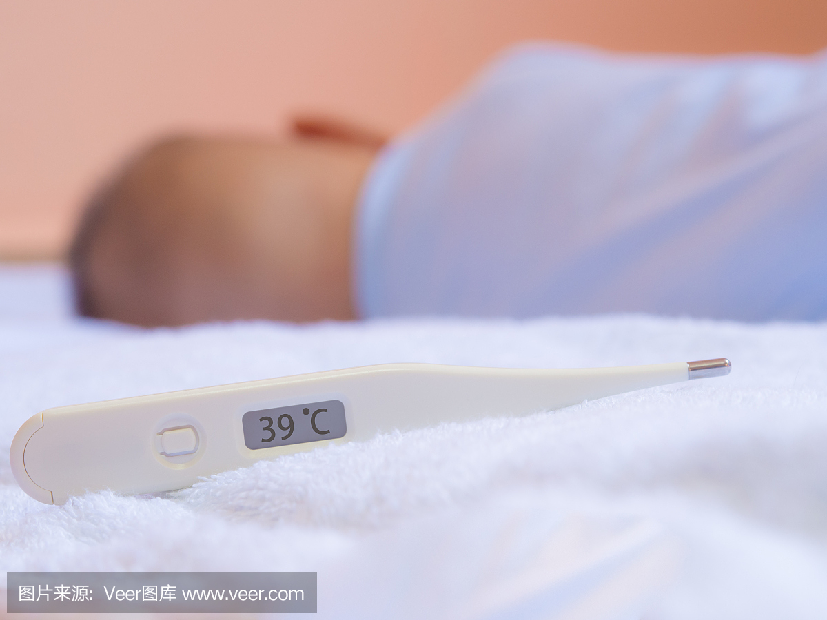 三十九度医疗温度计和婴儿睡在白色床垫上。测