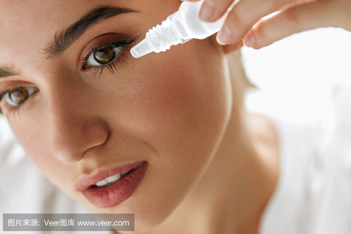 美丽的年轻女子在眼睛中应用眼药水。视觉概念