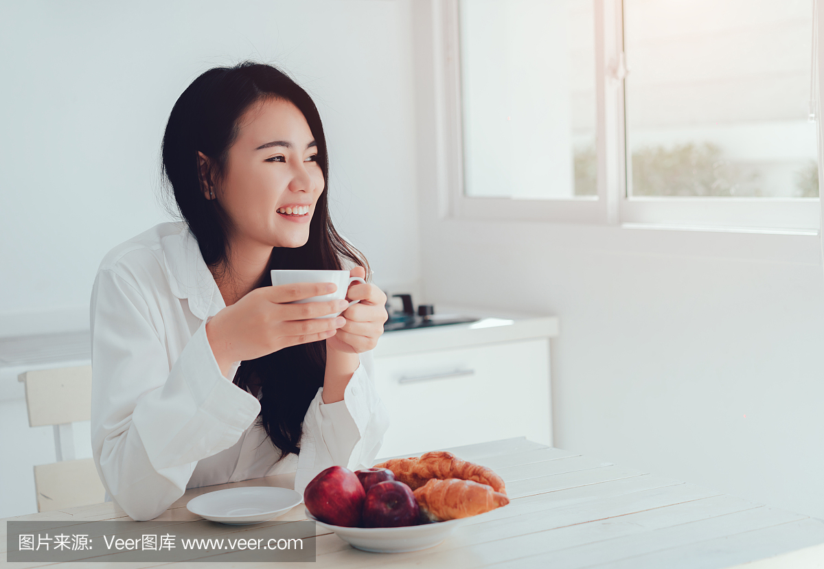 亚洲女人在早上喝咖啡和吃面包,苹果水果健康