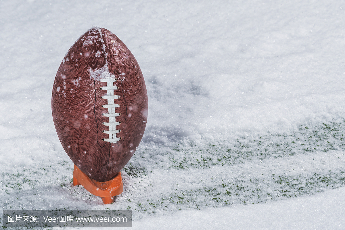 坐在雪地中的一条跑道上踢足球的美式橄榄球