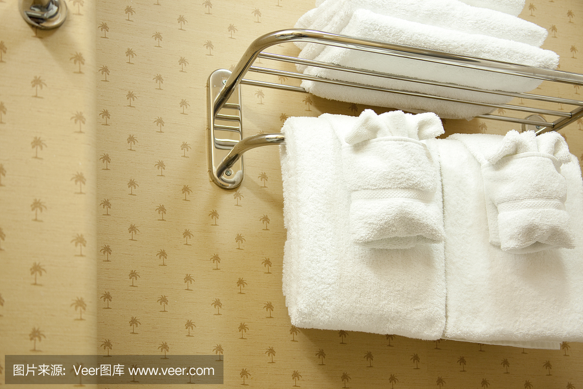 酒店浴室。折叠的白色毛巾在金属机架上。豪华