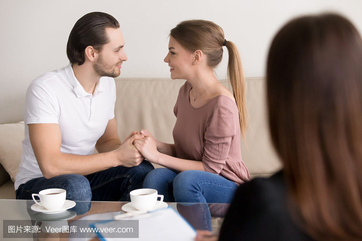 快乐微笑的年轻夫妇手牵着手,咨询心理学家,规