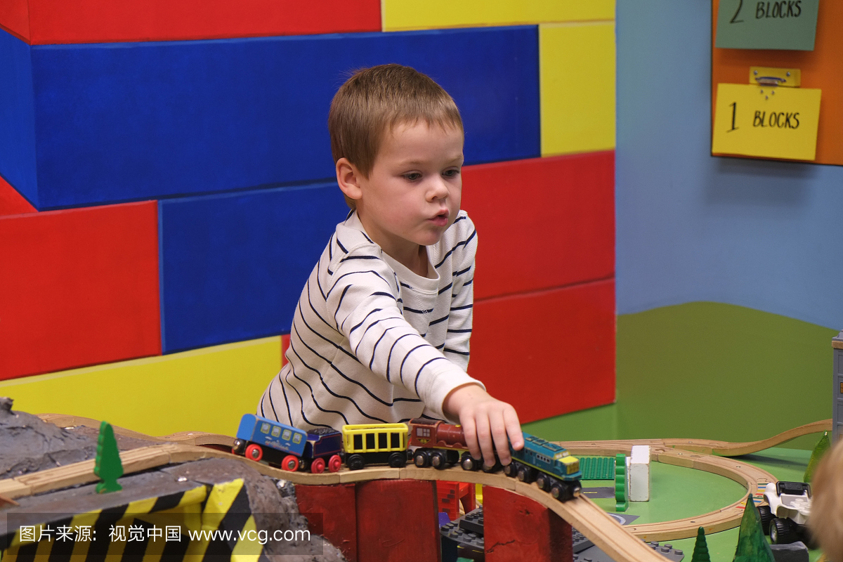一名四岁男孩在室内游乐中心玩玩具火车。