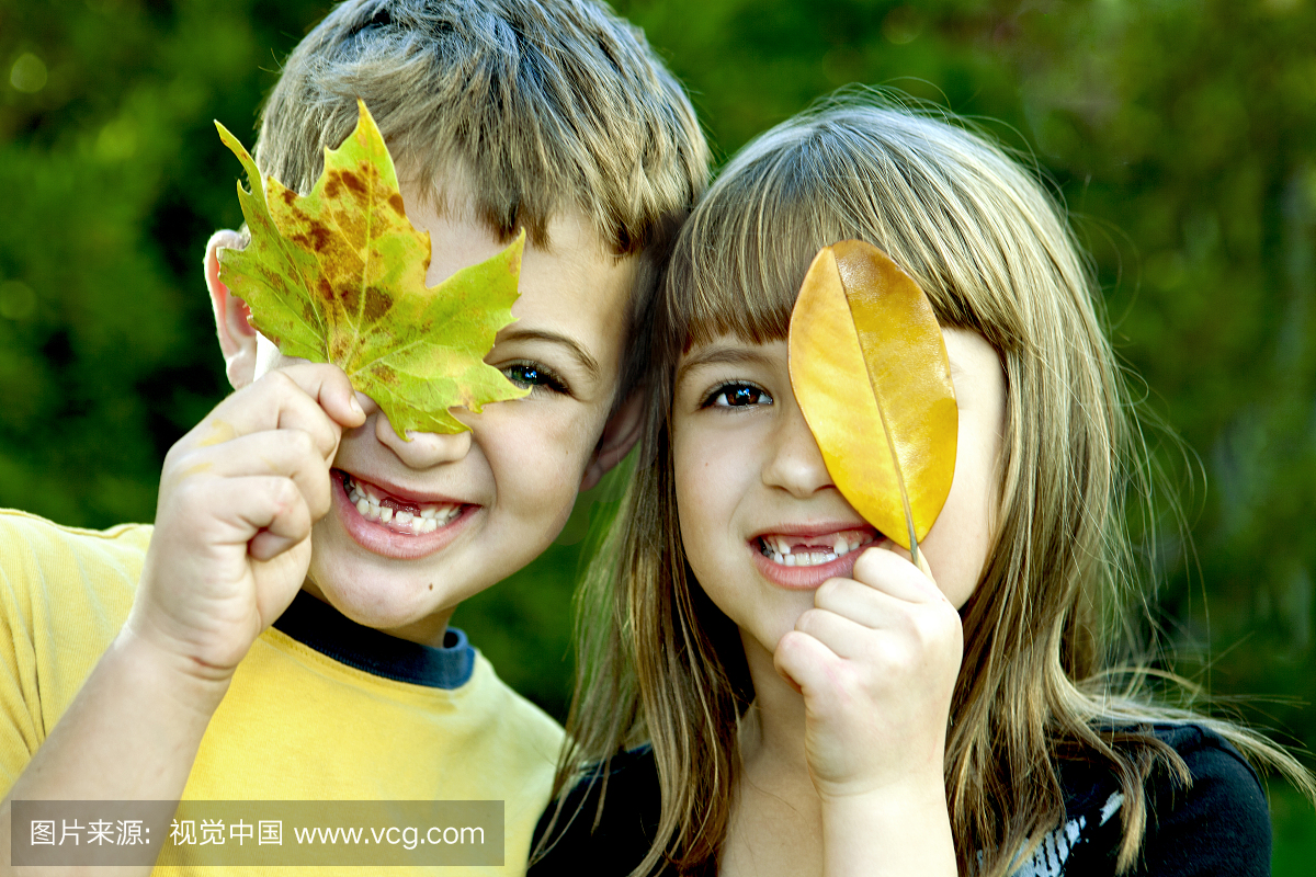 两个孩子用树叶遮住眼睛