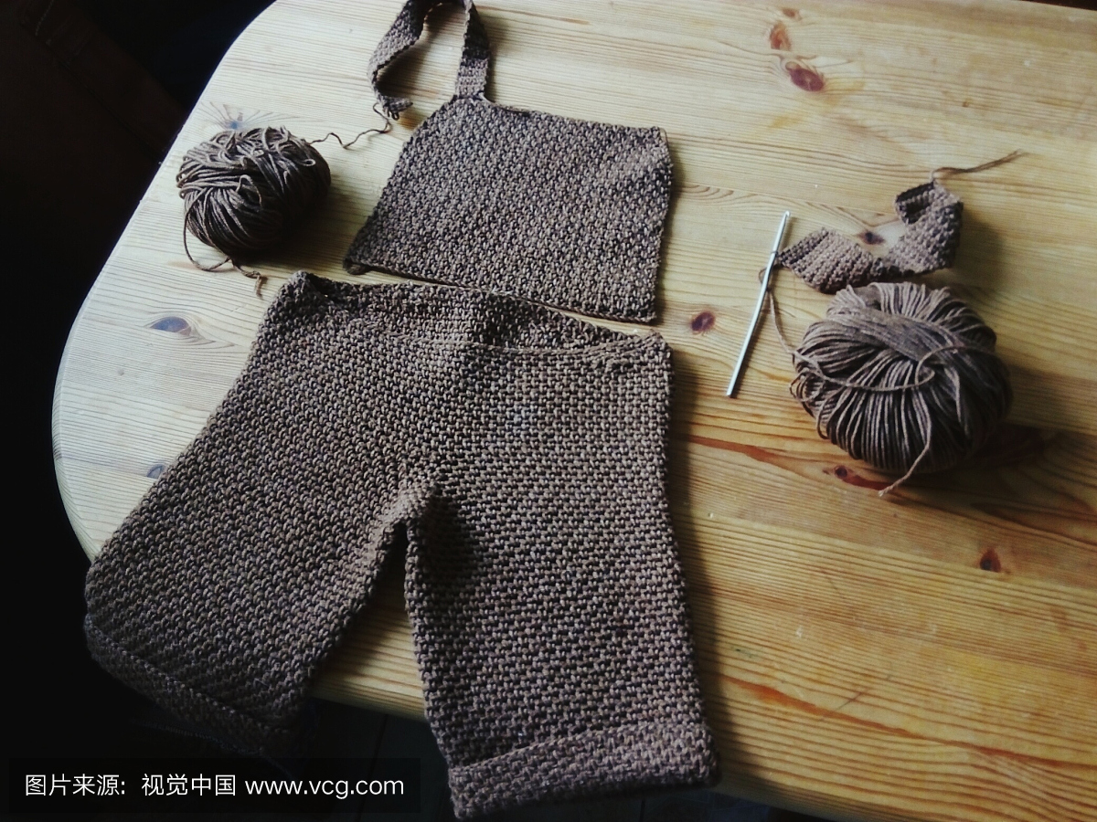 高角度视图的不完整的毛衣与钩针钩和羊毛在桌