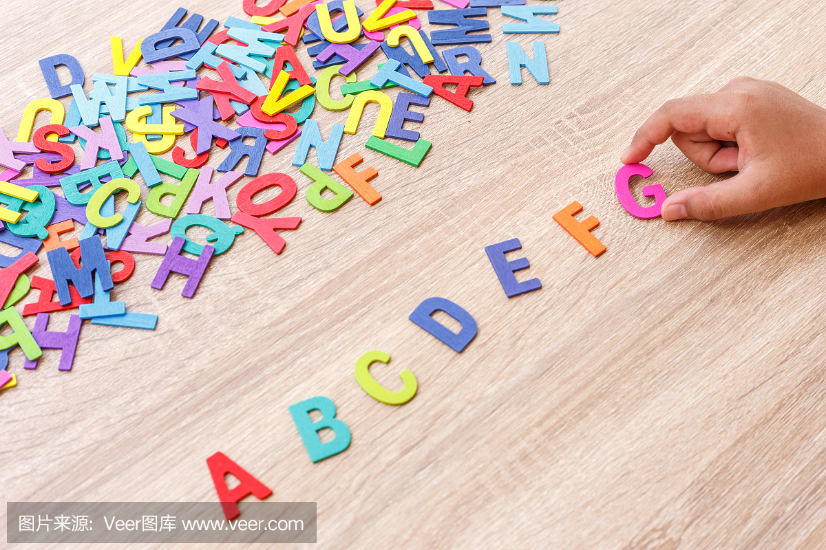 丰富多彩的木制字母表和手排序在G上灰色的木