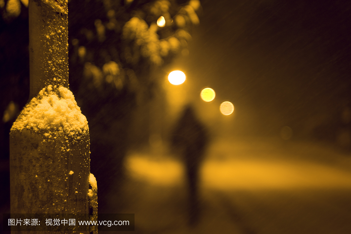 一个孤独的人在晚上走下雪街
