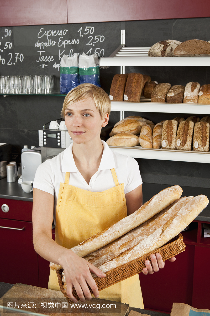 一名销售员拿着一篮长棍面包