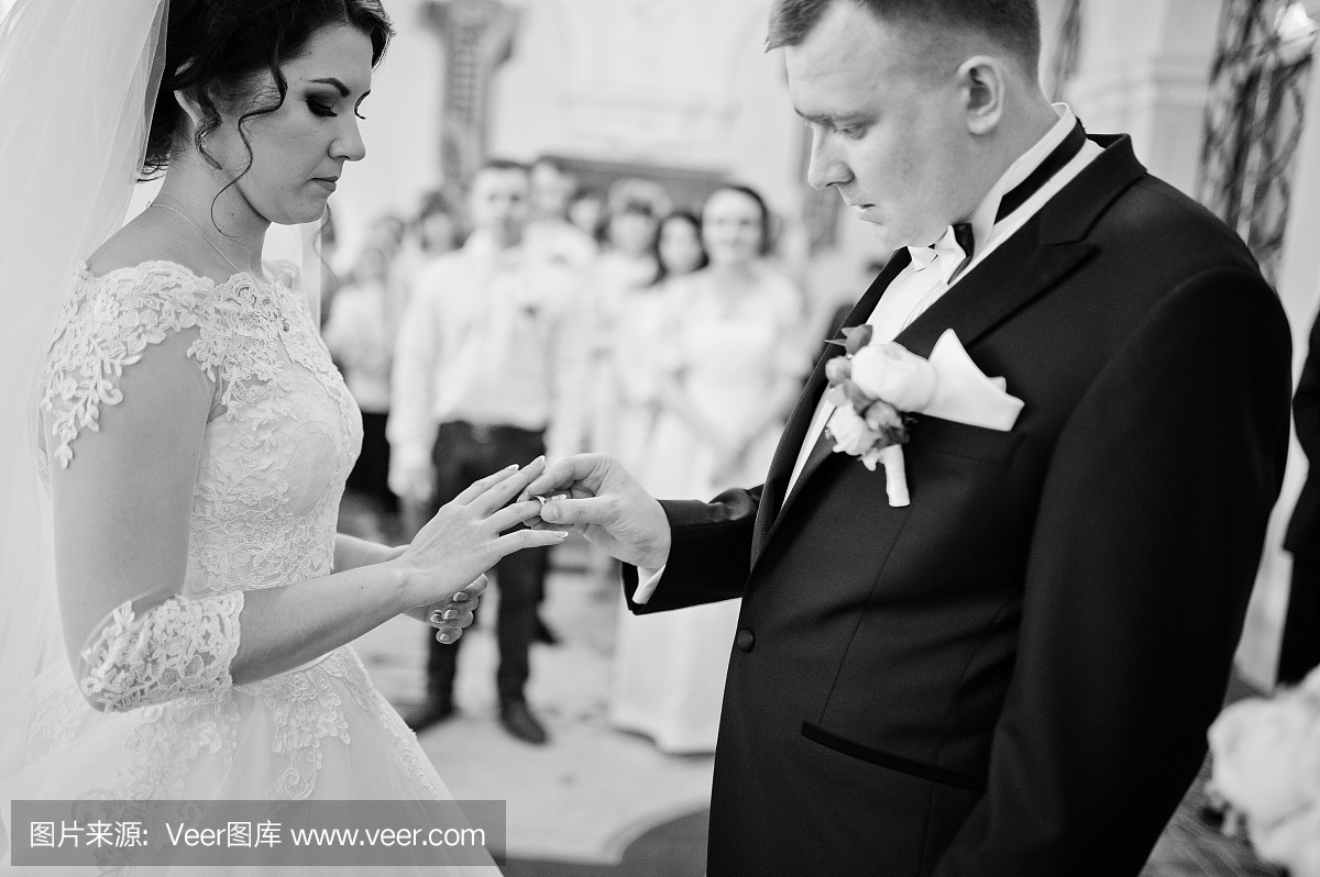 新郎在婚礼登记的大厅举行新娘的结婚戒指。黑
