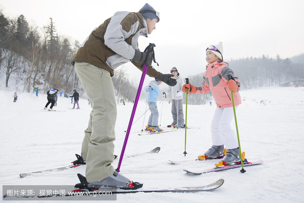 年轻的父母教子女滑雪