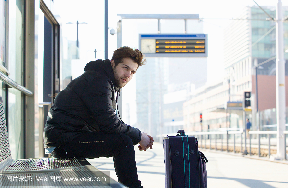 等待火车的年轻男子带行李箱旅行袋
