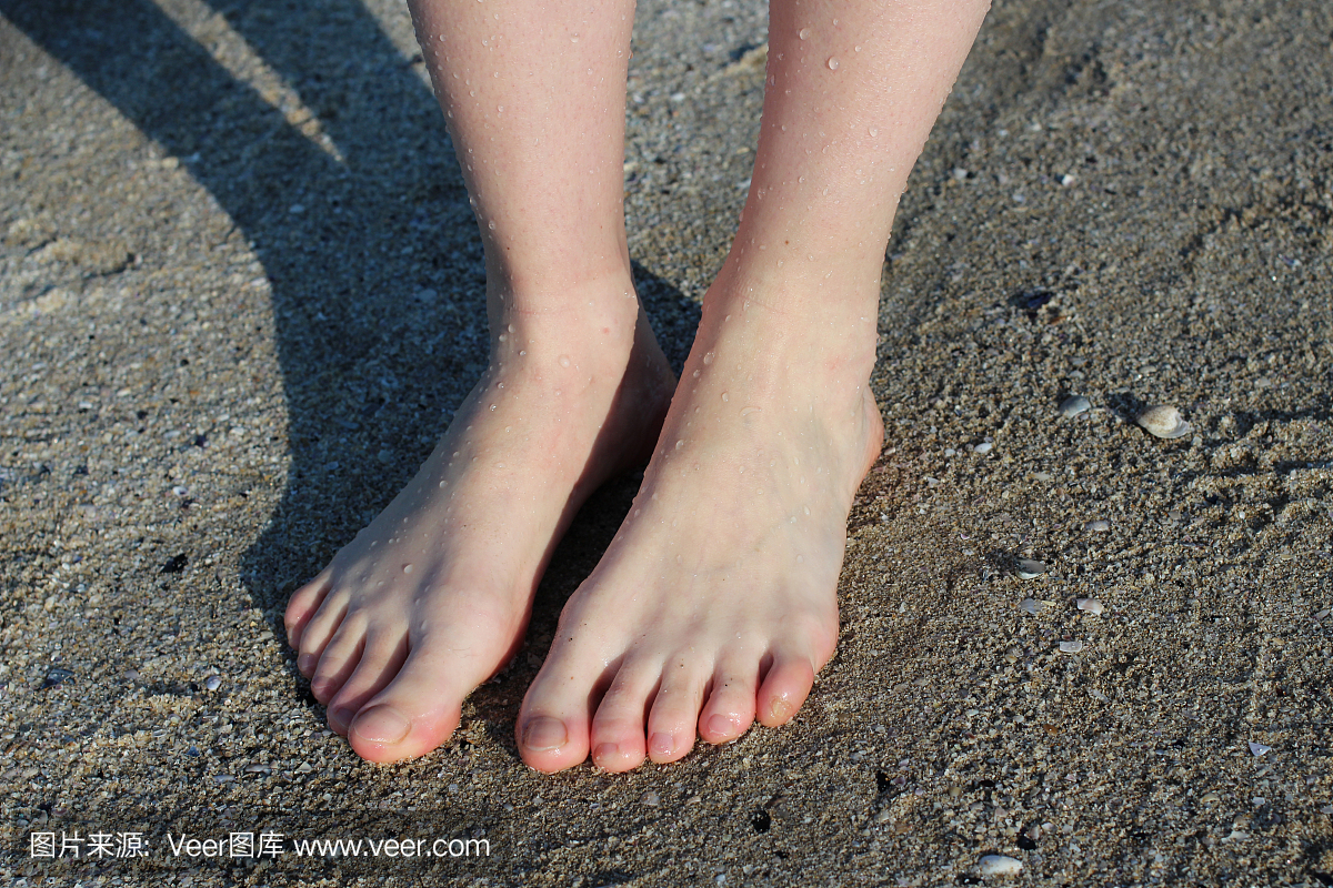 害羞的女孩脚站在沙滩上