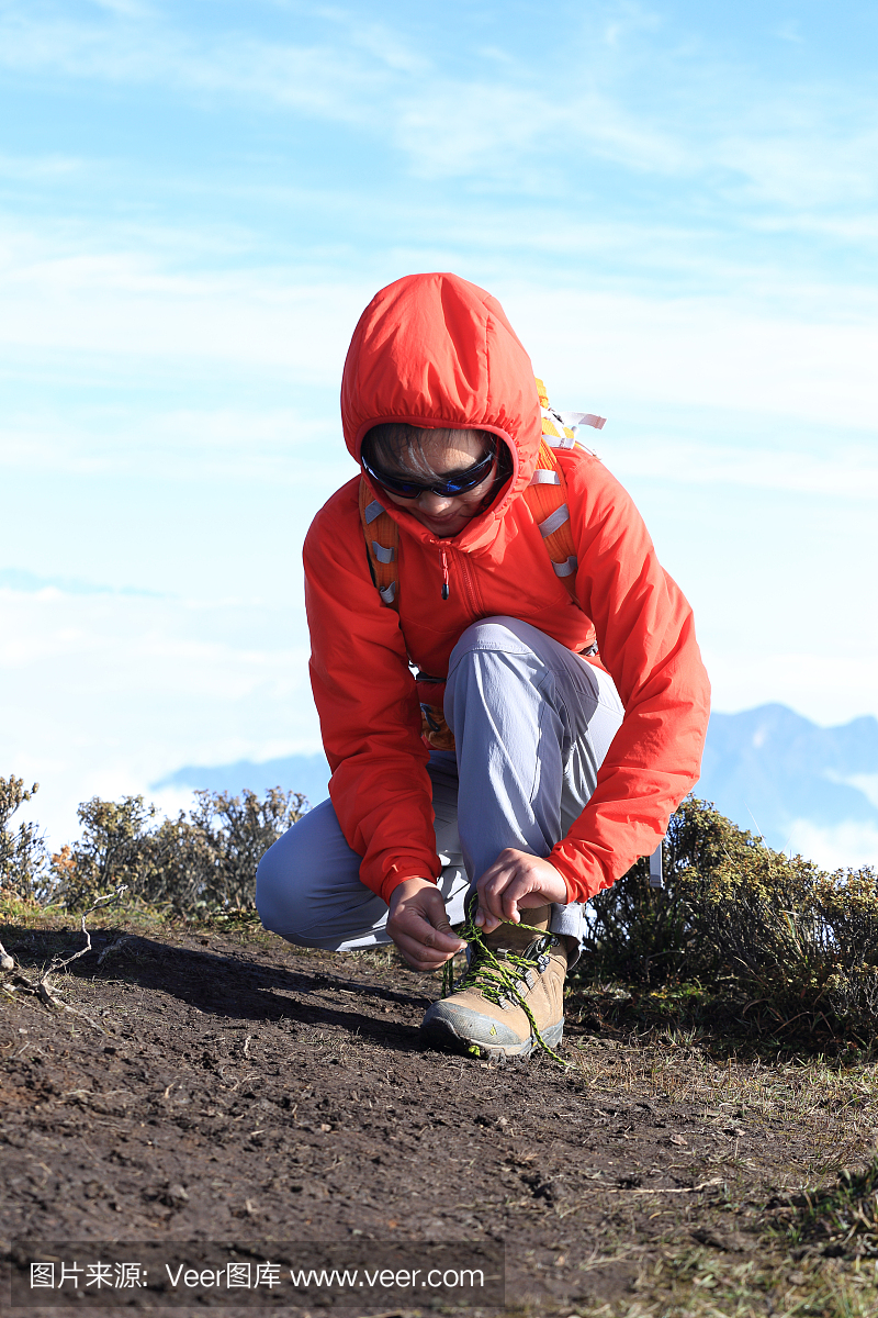 徒步旅行者徒步旅行者在美丽的山峰上绑鞋带