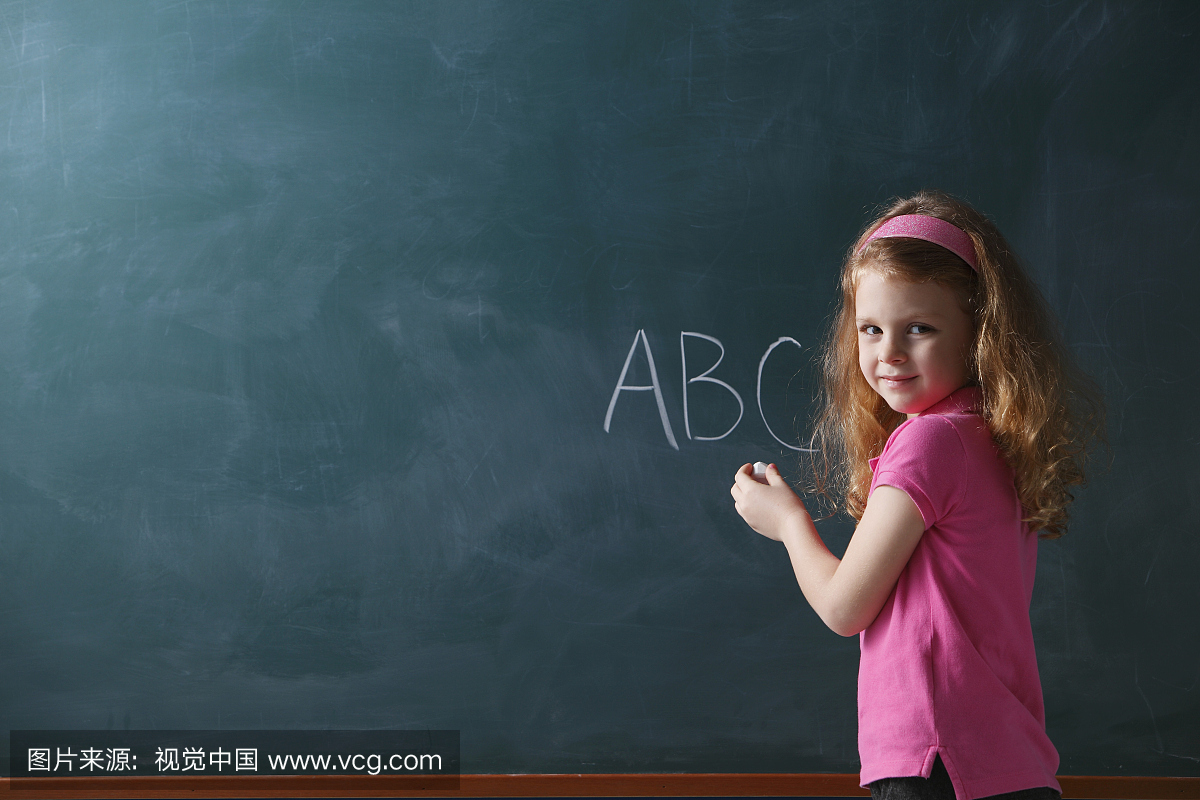 年轻女孩在粉笔板上写abc