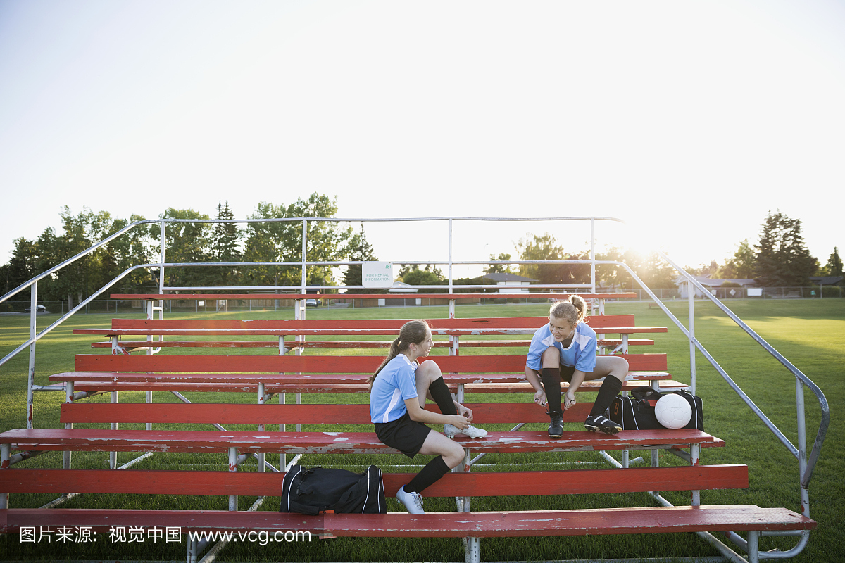 中学女生足球队友准备在漂白者身上穿上鞋子