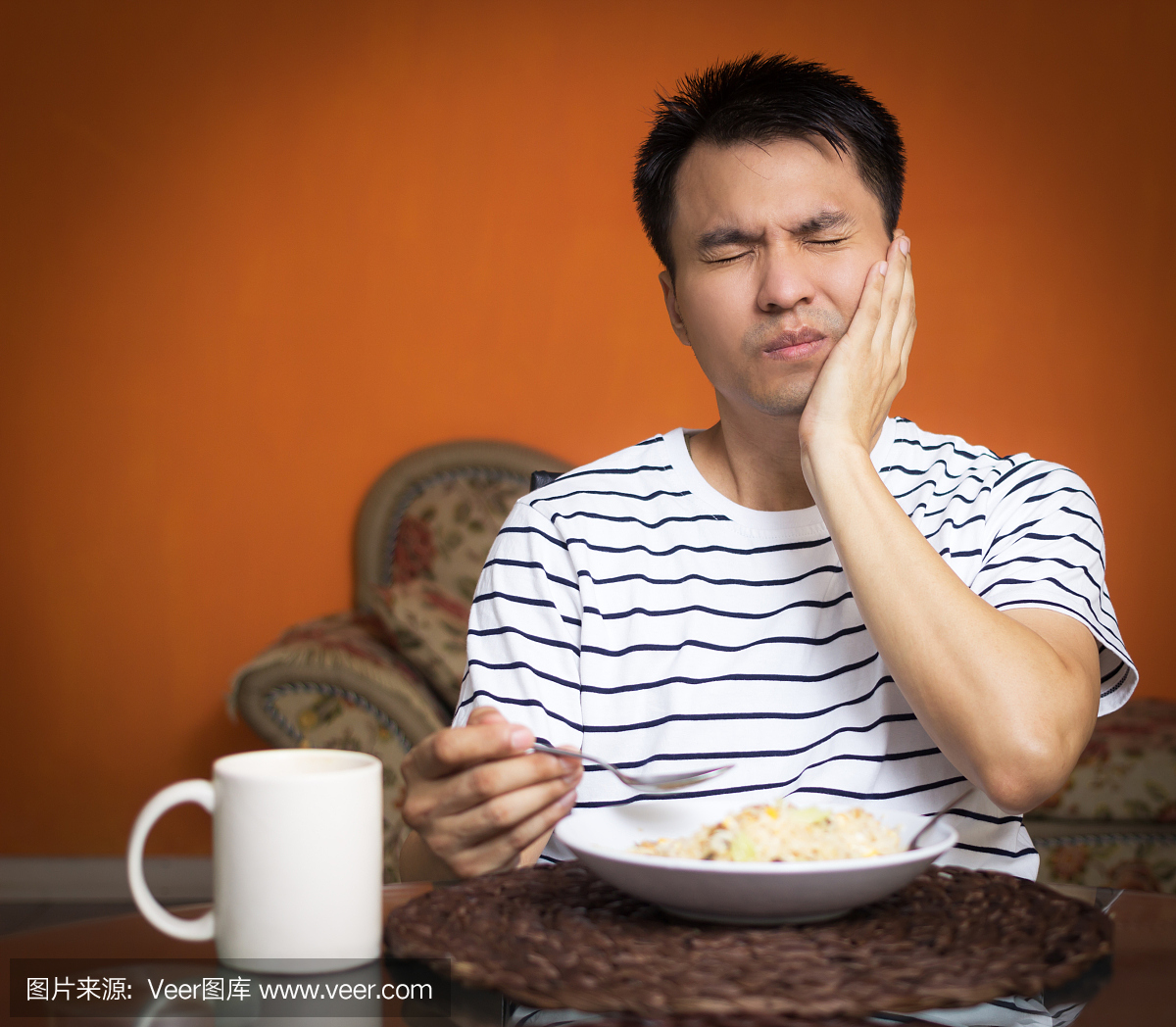 亚洲人在吃饭时有一个过敏的牙齿和牙痛