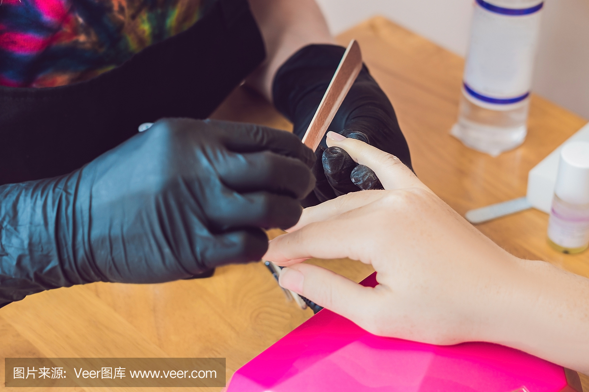 特写手指指甲护理由美容院的修指甲专家。美甲