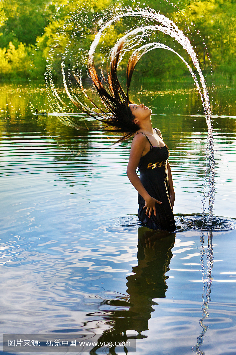 穿着的年轻女子将湿头发离开湖泊