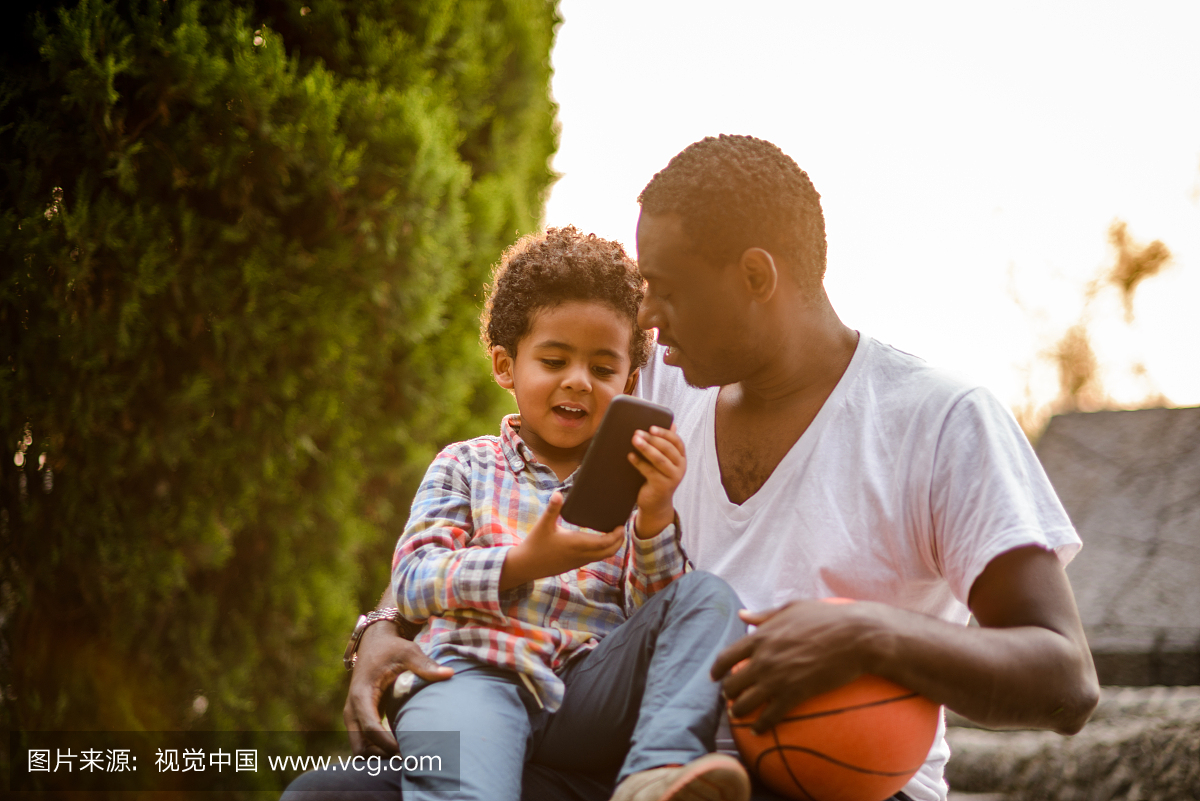 Father and son using mobile phone