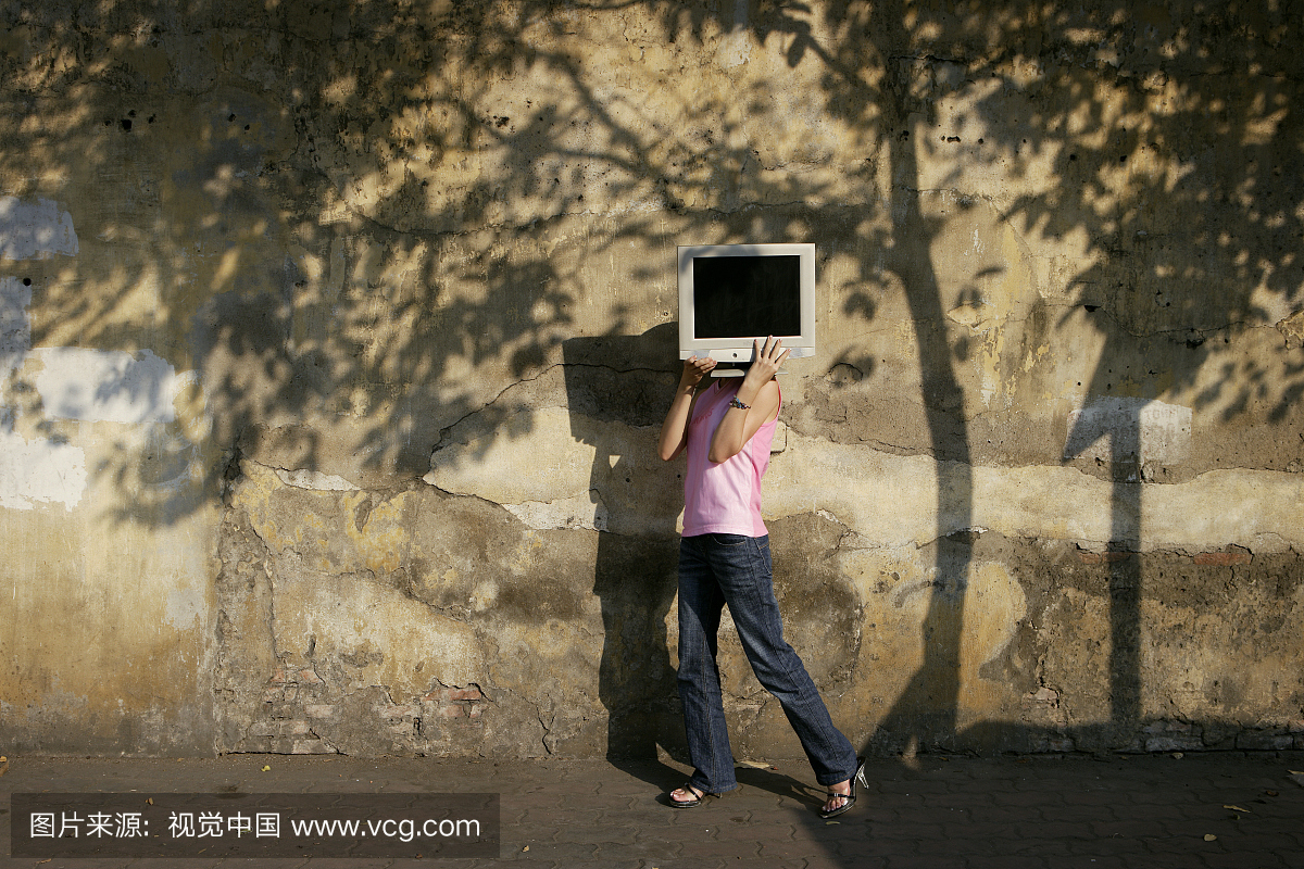 携带电脑显示器的年轻女子在街上的肩膀