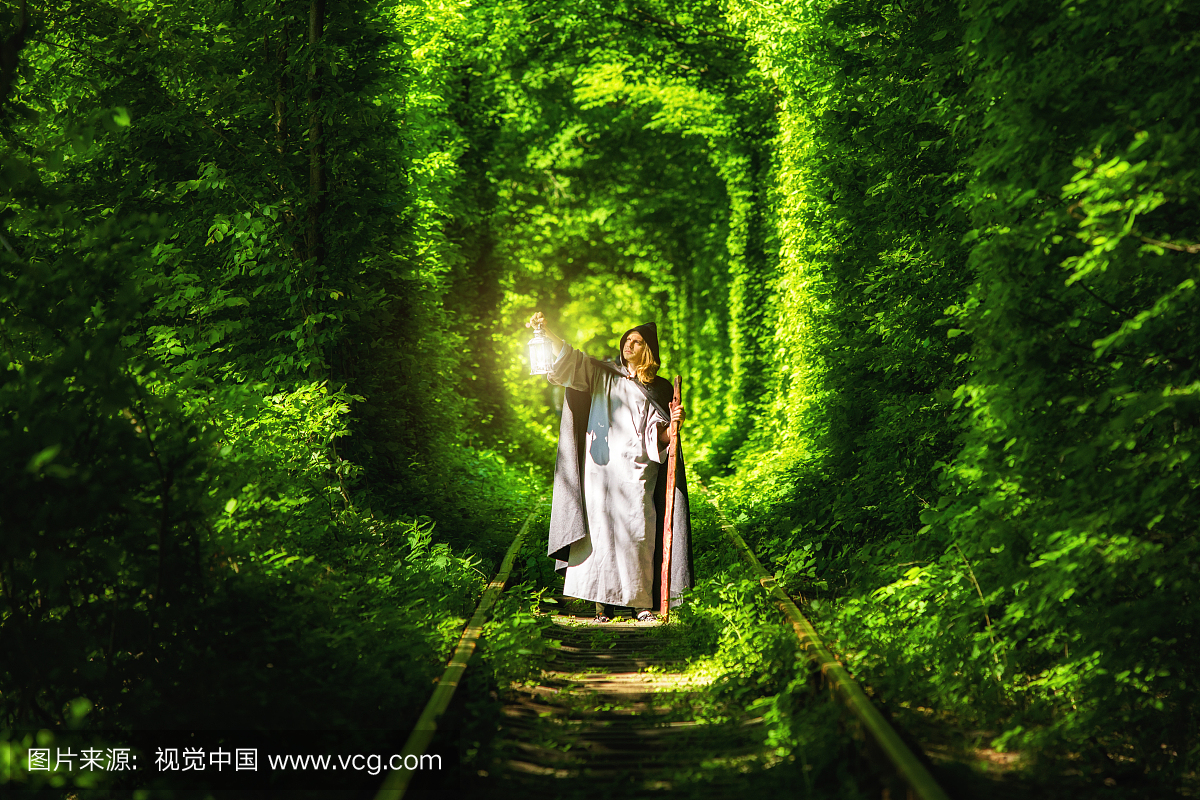 Wizard with a lantern in a tunnel of green forest