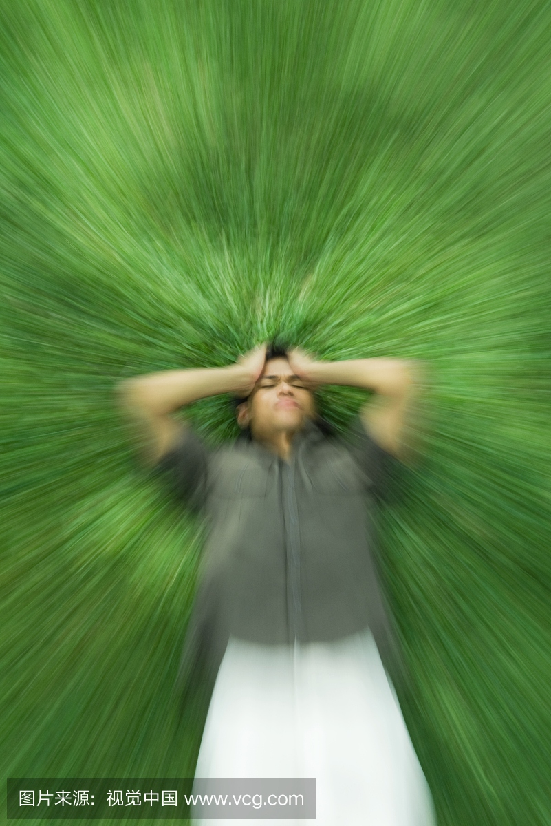 男人躺在草地上,闭着眼睛,抱着头,模糊的动作