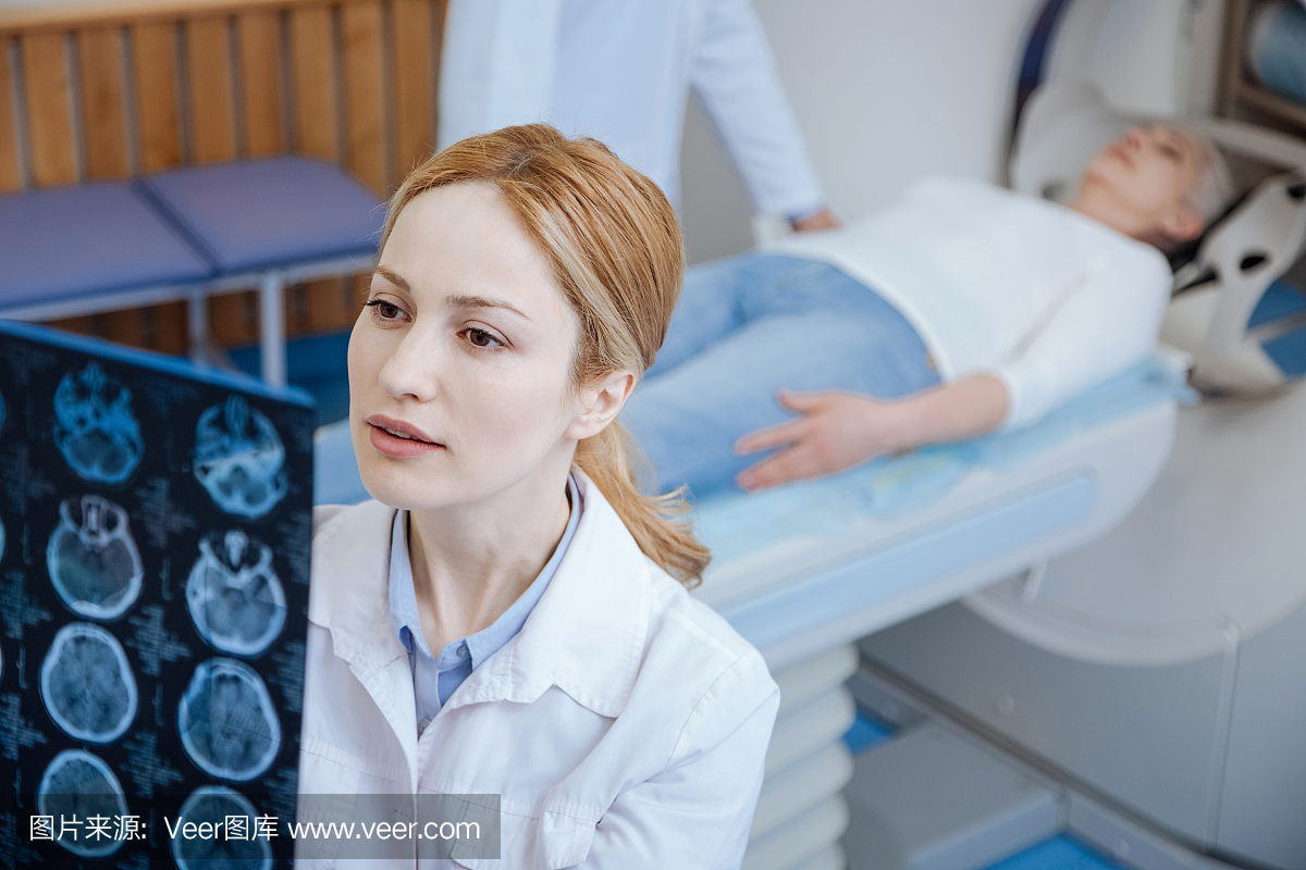 严重的女性肿瘤学家检查CT扫描的结果