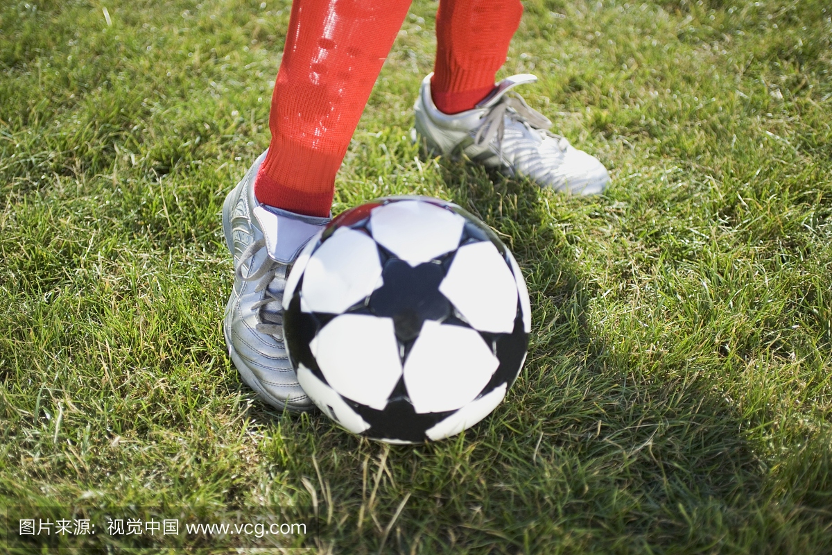 年轻的足球运动员的脚卷在一个足球与星形状在
