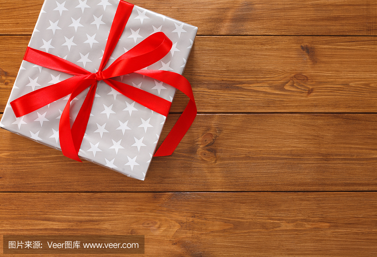 Present in gift box on wood background with co