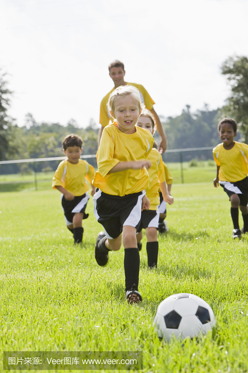教练与小孩踢足球追逐球的小组
