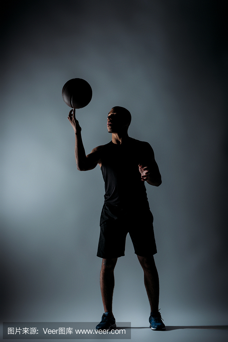 运动员在黑暗的房间里手指上旋转篮球球
