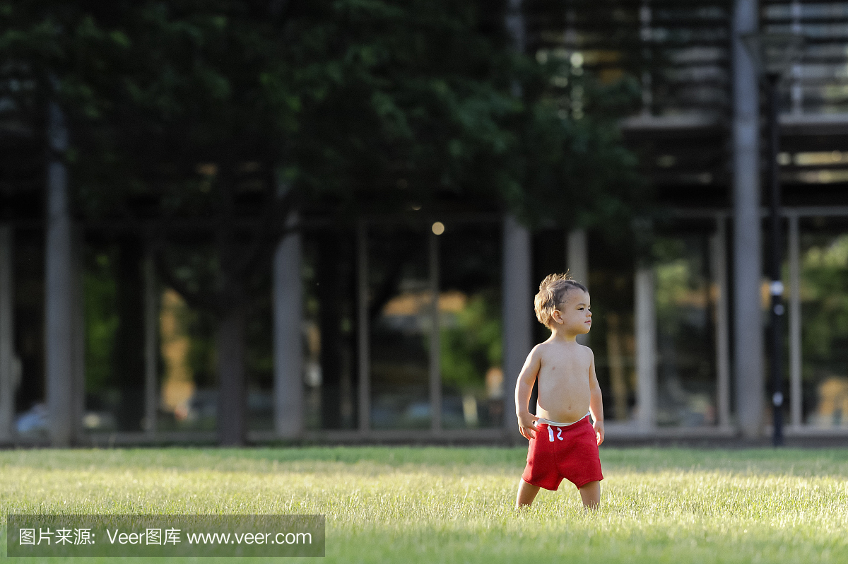 光着膀子的两岁男性蹒跚学步站在市区光着膀子