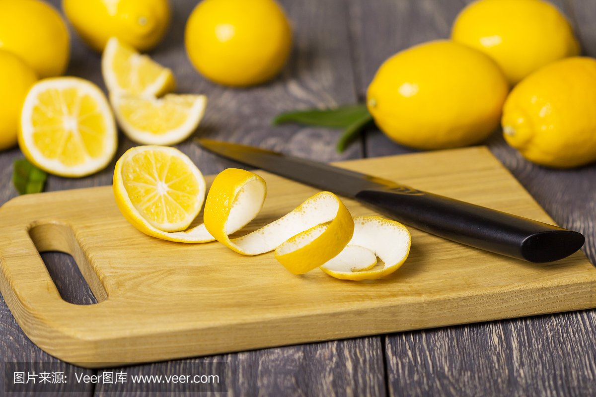 整个柠檬和果子片断与在木板的果皮在刀子旁边