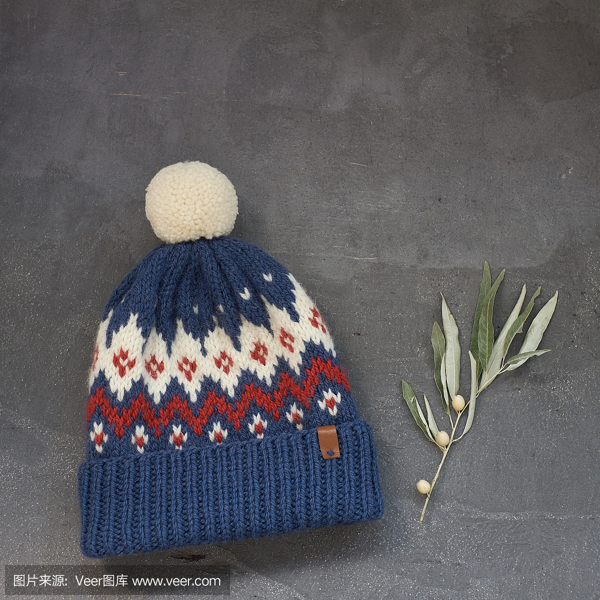 与灰色的背景上的提花图案的蓝色冬季帽子