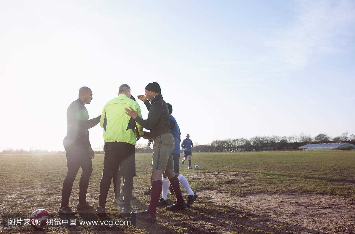 成熟的男性足球运动员在场上结合