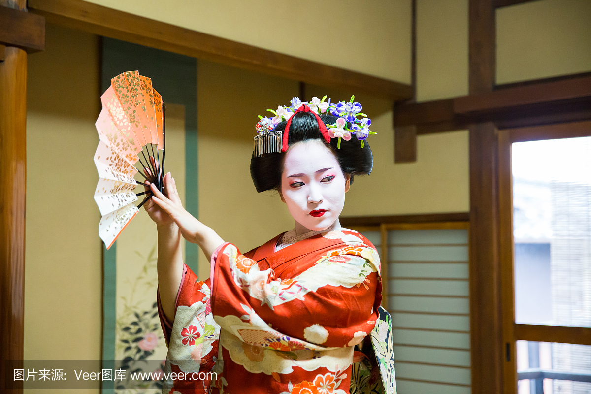 在日本榻榻米房间里用纸扇子跳舞的Maiko女孩