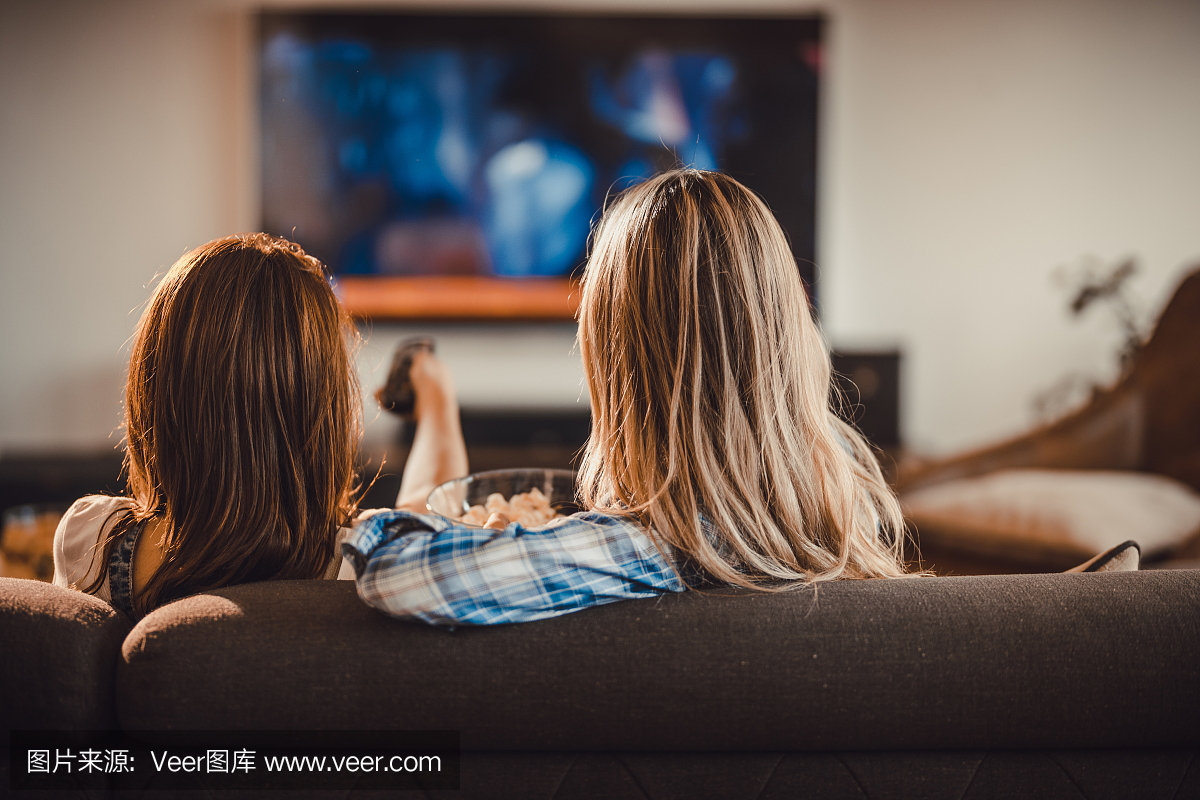 放松在客厅里的沙发上和看电影在电视上的两个
