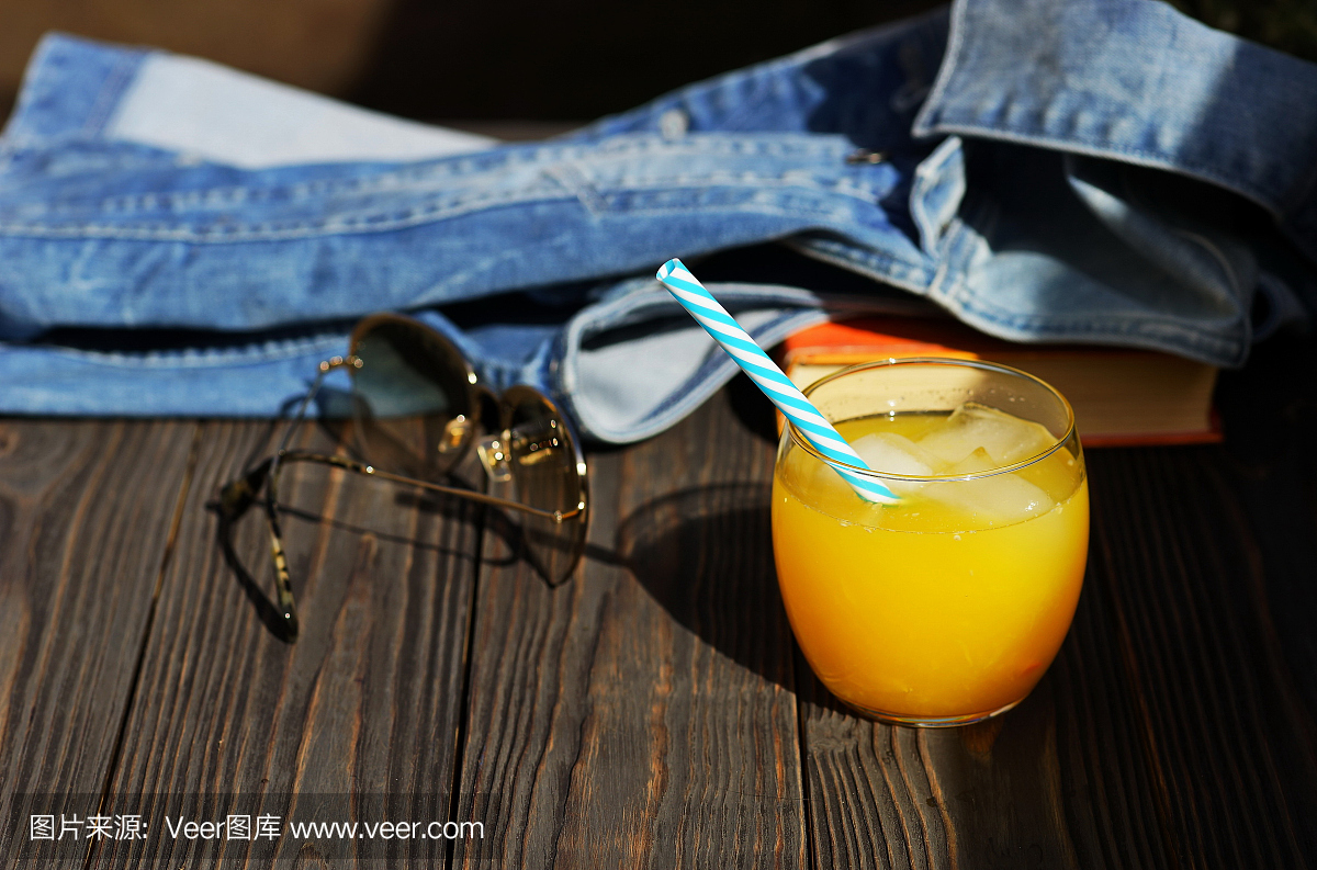 鲜榨橙汁在玻璃与冰块和榨汁机在木板上