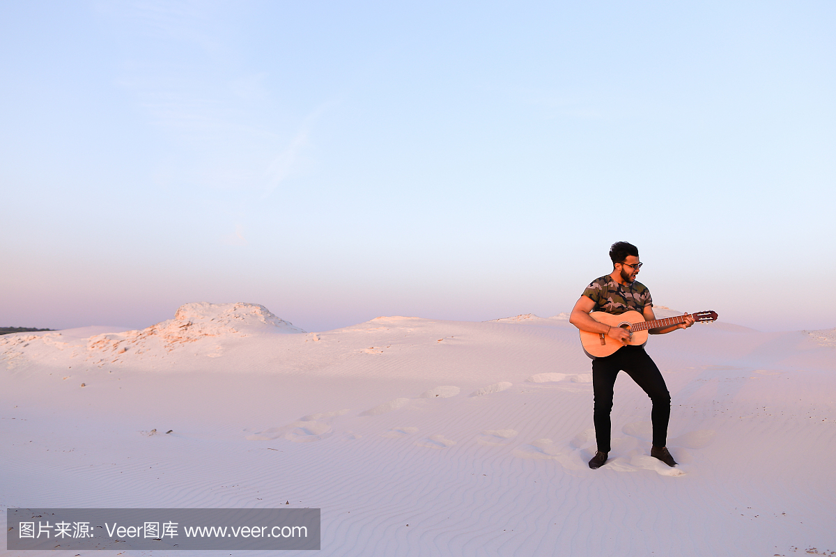 阿拉伯男人受到沙漠之美的启发,并弹吉他