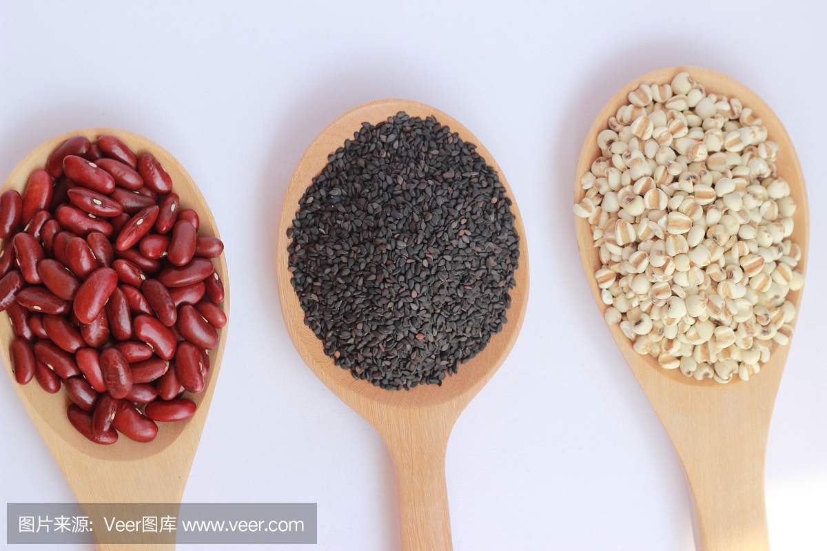 黑芝麻,红豆和小米在白色背景上的棕色木勺子