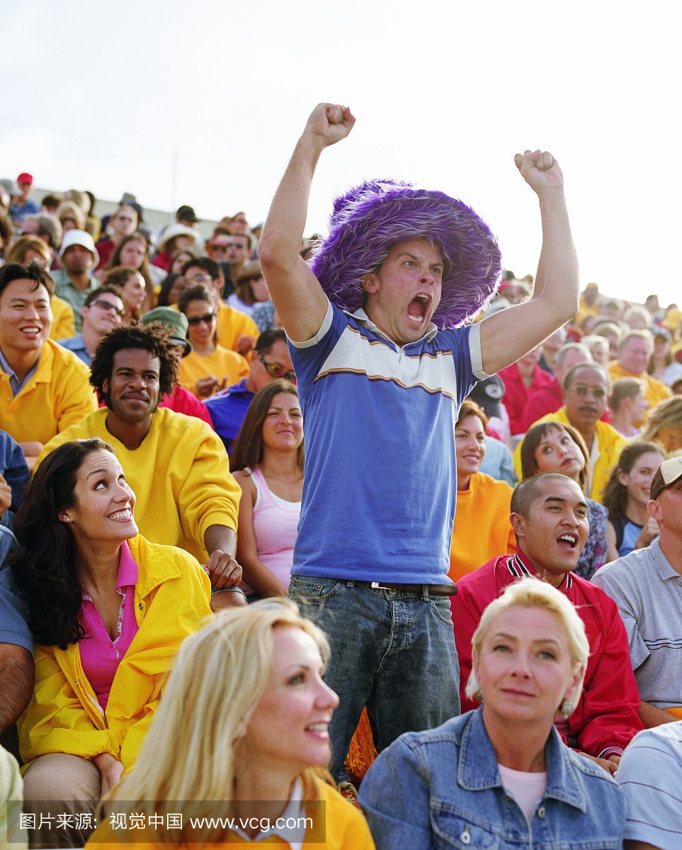 年轻人穿着紫色的帽子,站在体育馆的人群中,欢