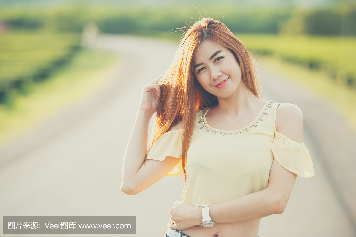 肖像微笑泰国美丽的女孩在阳光下的道路上