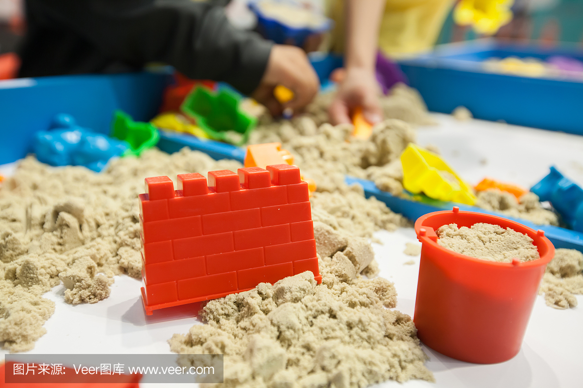孩子们玩沙子上的沙子塑料模具玩具。背景模糊