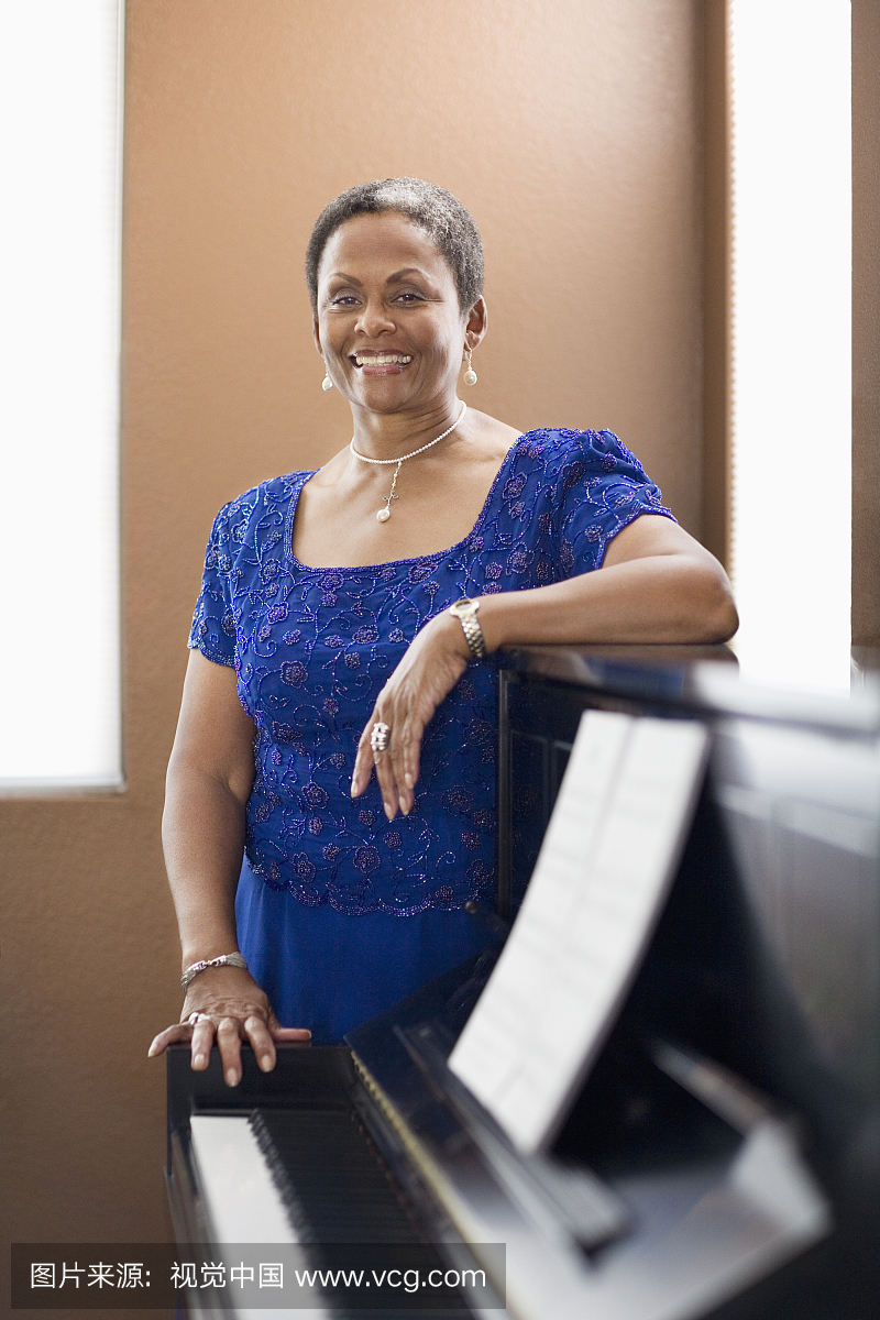非洲女子在晚礼服倾斜钢琴