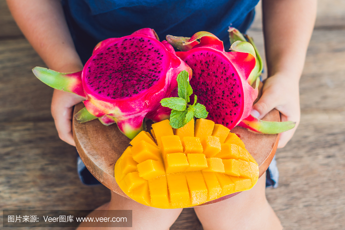 在男孩手中切丁火龙果和芒果