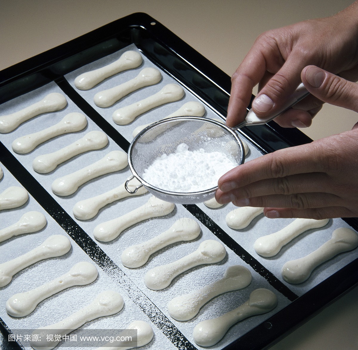 Close-up of hand sprinkling icing sugar with sie