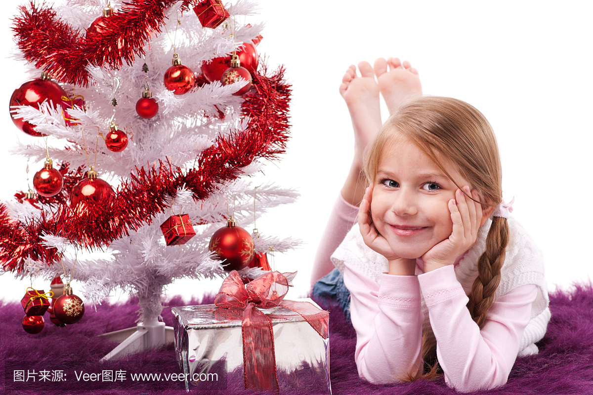 美丽的小女孩躺在圣诞树下面
