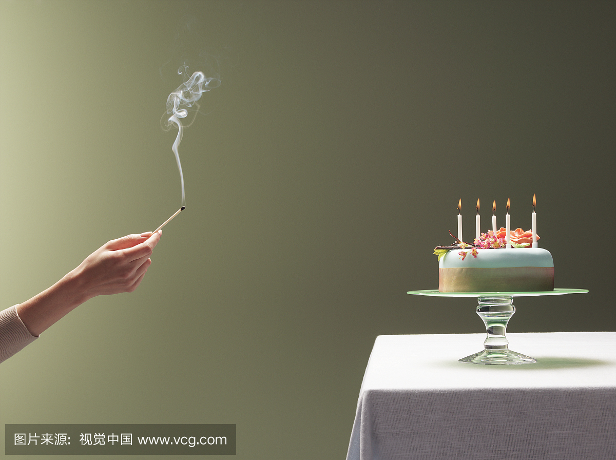 拿着吸烟的女人在蜡烛附近点燃生日蛋糕