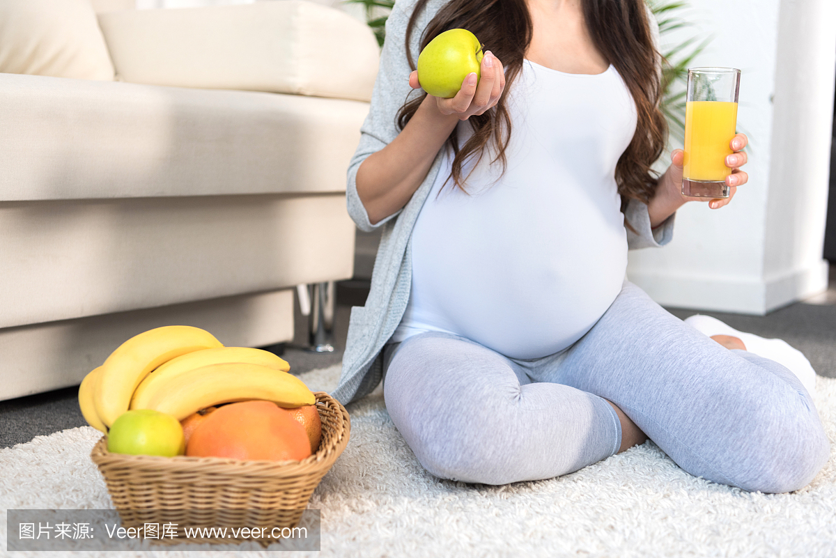 拿着苹果和汁液的孕妇