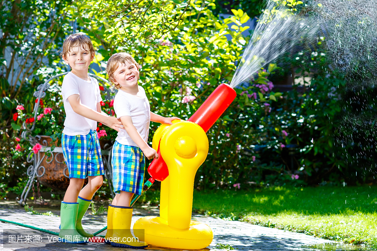 两个小孩孩子玩一个花园软管喷水器